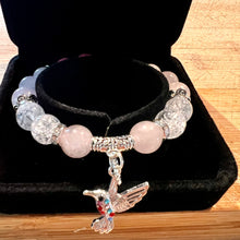 Load image into Gallery viewer, Bracelet with pink beads and hummingbird charm on a black velvet stand.
