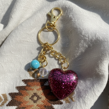 Load image into Gallery viewer, Keychain with a glittery heart charm on a textured fabric background