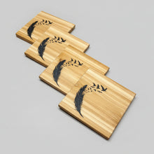 Load image into Gallery viewer, Set of wooden coasters with feather design on a TABLE

