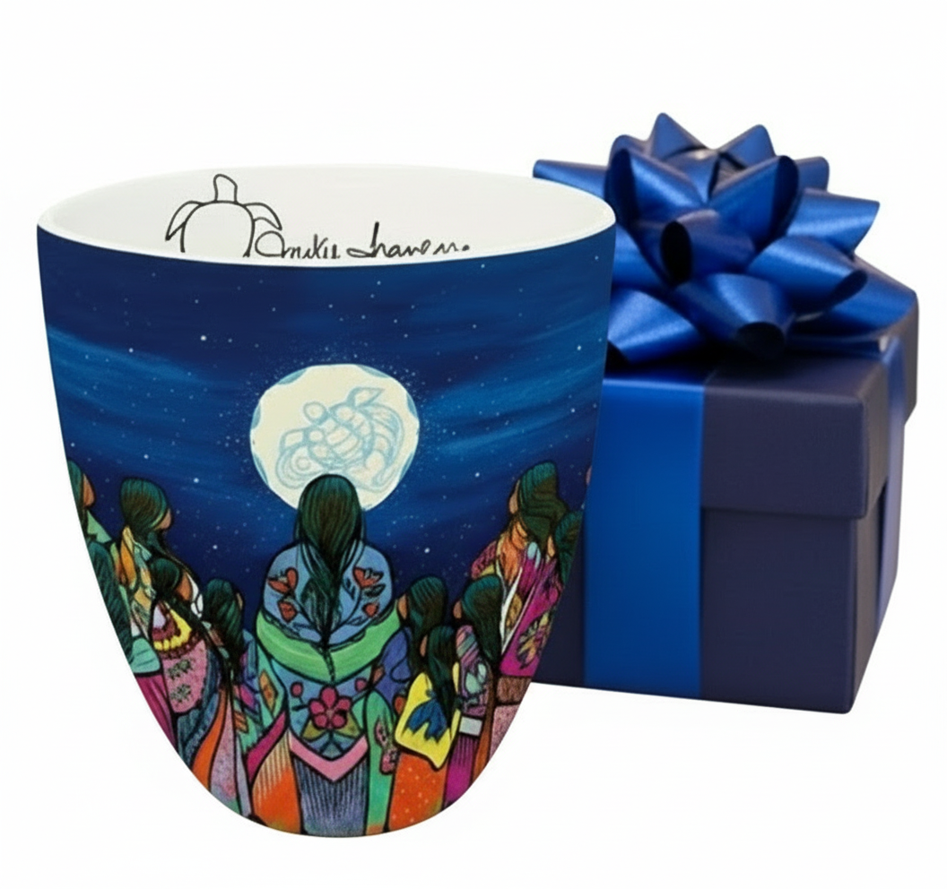 Colorful mug with artistic design and blue gift box on a wooden surface