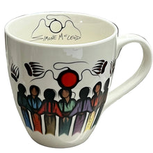 Load image into Gallery viewer, A white ceramic coffee mug featuring a colorful illustration of figures holding hands and black abstract line art, with the text 'Simone McLeod' written inside the rim, set on a gray countertop.