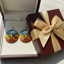 Load image into Gallery viewer, Pair of earrings with hummingbird and flower design on a wooden surface