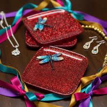 Load image into Gallery viewer, Red glittery cases with dragonfly designs on a wooden surface with colorful ribbons.