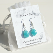 Load image into Gallery viewer, Turquoise earrings on a Mocs N More branded card, displayed on a wooden surface.