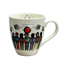 Load image into Gallery viewer, A white ceramic coffee mug with a colorful hand-painted style illustration of figures and abstract symbols, sitting on a gray tabletop.