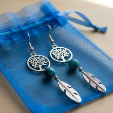Load image into Gallery viewer, Silver tree of life earrings with turquoise beads and feathers on a 'Mocs N More' card.
