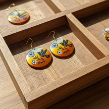 Load image into Gallery viewer, Pair of earrings with bird and flower design on a wooden surface