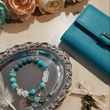 Load image into Gallery viewer, Turquoise beaded bracelet on a silver tray with flowers, keys, and a blue pouch in the background.