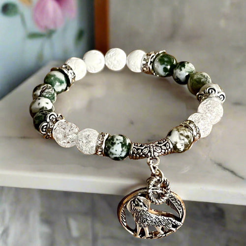 Bracelet with green and white beads and an elephant charm on a wooden surface