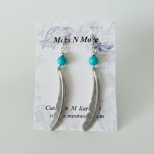 Load image into Gallery viewer, Feather earrings with turquoise beads on a display card, brand 'Mock N More' visible.