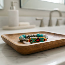 Load image into Gallery viewer, Beaded bracelet with turquoise, silver, and red beads on a wooden surface
