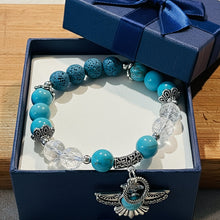 Load image into Gallery viewer, Turquoise beaded bracelet with silver charms on a wooden surface