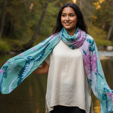 Load image into Gallery viewer, Indigenous woman wearing the Hummingbird signature scarf as a wrap near a river or forest