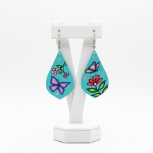 Load image into Gallery viewer, Teal teardrop earrings with Indigenous butterfly and flower art on white jewelry display