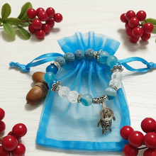 Load image into Gallery viewer, Bracelet with turtle charm on a blue drawstring bag against a wooden background